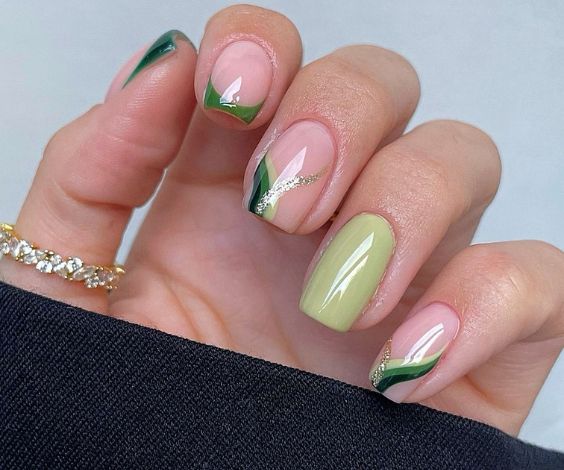 Short squoval nails with leafy green colors and glitter art. 